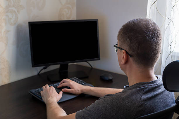 istock Man with short hair working on computer at desk with modern workspace and soft lighting 2244838316