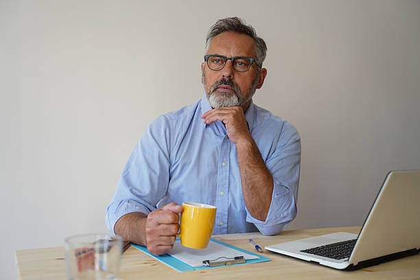 istock Middle-aged man working on a laptop, managing finances, sitting at a desk 2244841763