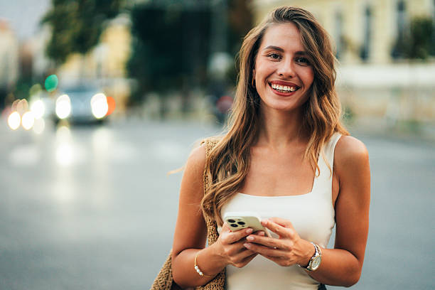 istock Beautiful woman using mobile in the street 2244842249