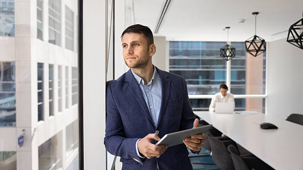 istock Company manager man standing at office window with tablet 2244842750