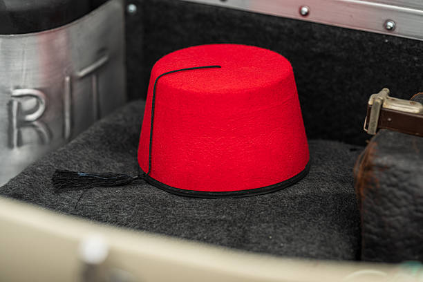 Red fez hat placed in vintage car trunk setup.