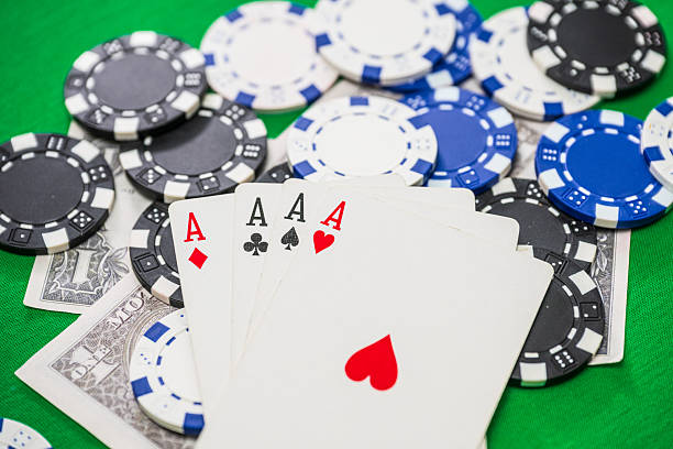 istock Four aces poker hand with chips and cash.. 2244844763