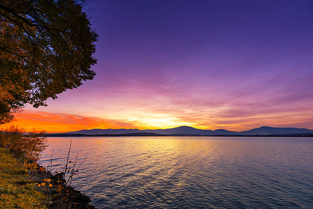 Vibrant Sunset Over Calm Lake with Mountain Silhouette