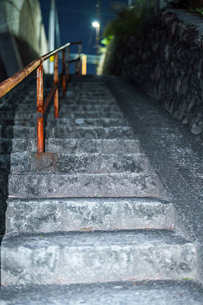 Night stone steps with a rusty handrail leading up an alley