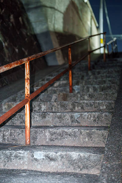 Night stone steps with a rusty handrail leading up an alley