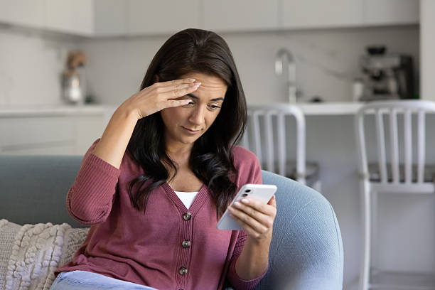 istock Puzzled Latin smartphone user woman touching head 2244848276
