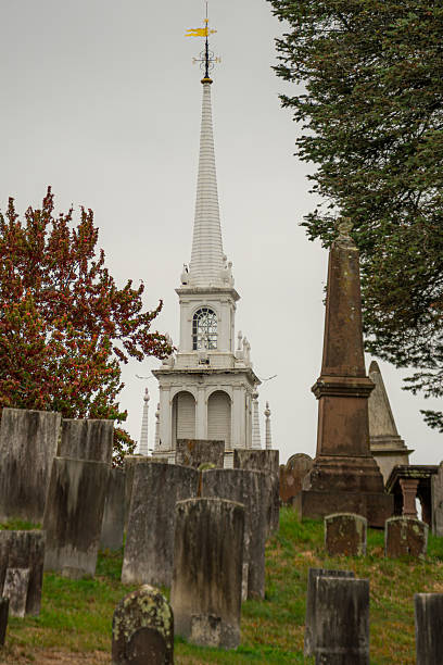 Old Moss Covered Headstones in Wethersfield Village Cemetery occupy the foreground with a white church steeple in the background, Wethersfield, Connecticut, New England