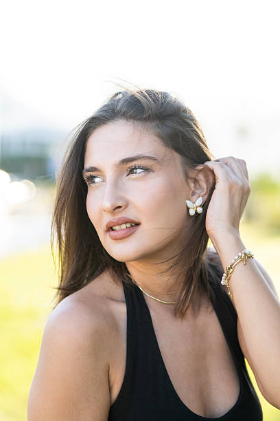An Asian woman portrait is wearing diamond earring, looking at side down with yellow background. Portrait of beautiful Asian woman dressed in a posh jewelry set of diamond ring, bracelet and earrings