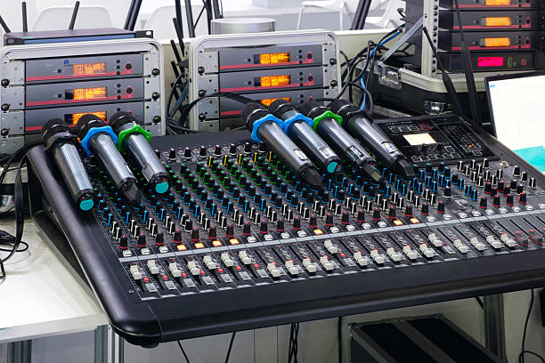 istock A black mixing board with a microphone stand on it. stand has a blue and green microphone 2244851986