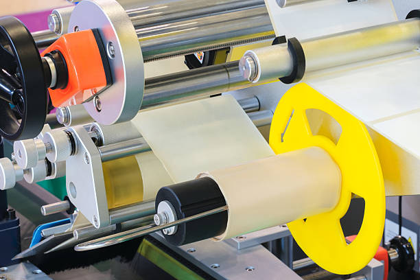 istock roll of white paper is passed through the machine. printer and sticker machine, which is used for printing and applying stickers to packaging industrial products. Concept of precision efficiency 2244852104