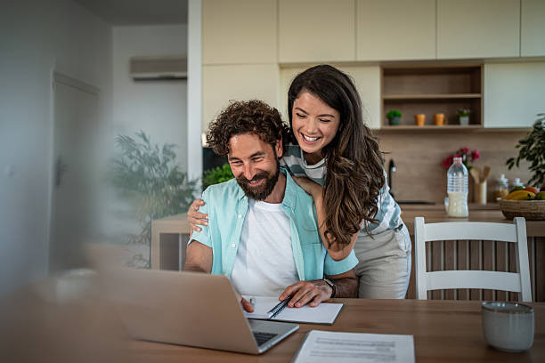 istock Young couple managing home finances using laptop at kitchen table 2244852411