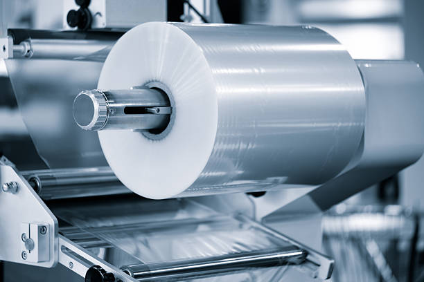 istock Automatic polyethylene plastic bag production machine with lighting effect. Close-up of  roller of plastic bag production machine in light blue scene. product packaging concept 2244852418