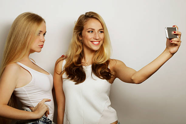 two young funny women taking selfie with mobile phone