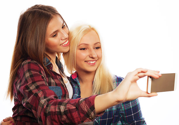 Two pretty hipster girls taking selfie. Isolated on white background.
