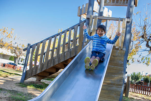 Smiling child enjoying a fun slide ride at the playground on a bright autumn day.