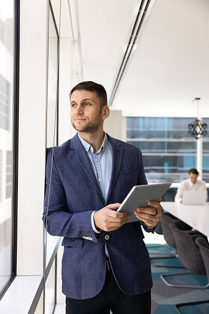 istock Positive dreamy male executive holding digital touchpad 2244861782