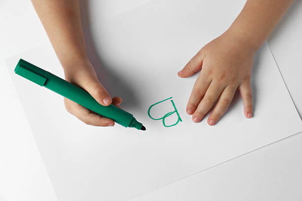 istock Little child writing letter B on paper sheet at light table, top view 2244862172