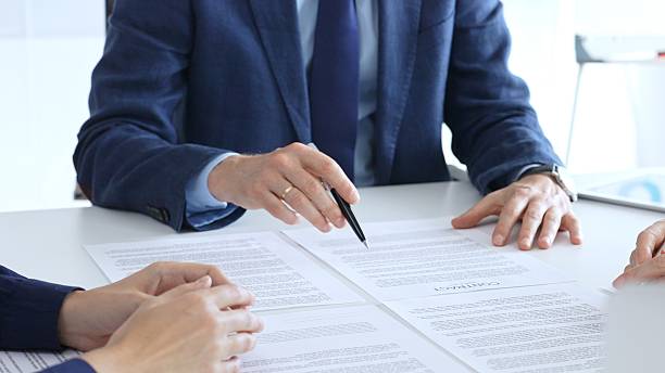 istock Businessman or lawyer pointing into contract papers with black pan and discussing documents with colleagues in a bright office. Business people concept 2244863400