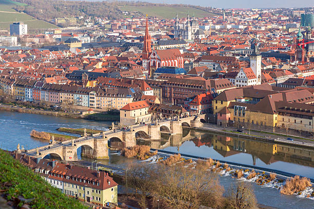 Historic Old Main Bridge with statues over Main River in Wurzburg, Germany with people walking across on sunny day