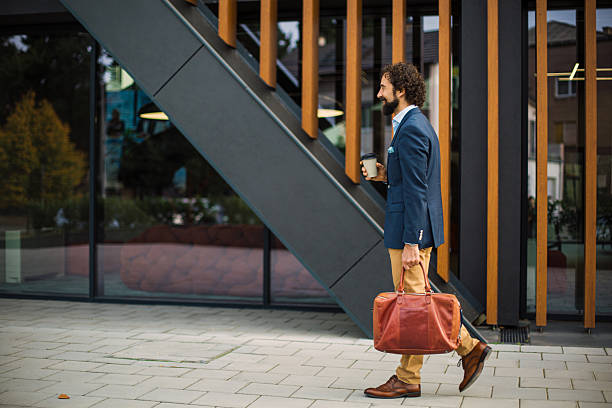 istock Businessman walking with coffee and briefcase in urban setting 2244864680