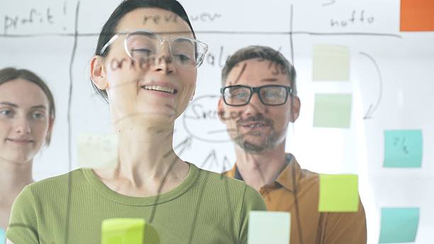 istock Professional team brainstorming project strategy, placing colorful sticky notes on glass board, analyzing data, sharing insights, developing collaborative solutions 2244865002