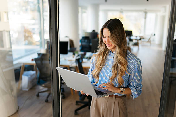 istock Businesswoman standing in modern office using laptop 2244866140
