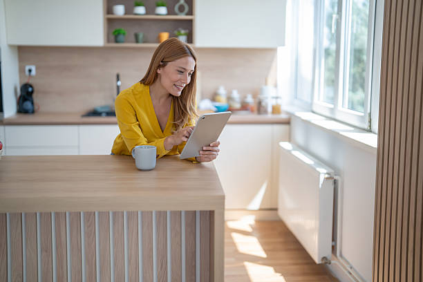 istock Smiling woman using digital tablet in modern kitchen while enjoying morning coffee 2244867530