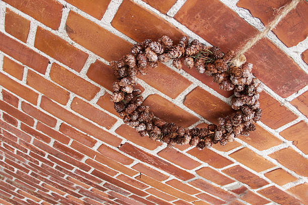 Decorative pinecone wreath hanging on a rustic brick wall backdrop, showcasing natural charm and seasonal warmth