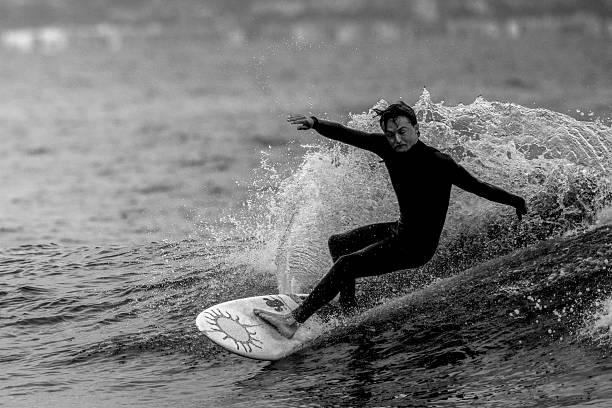 Adult man in a wetsuit entering the sea with a paddleboard, enjoying watersports and a healthy lifestyle