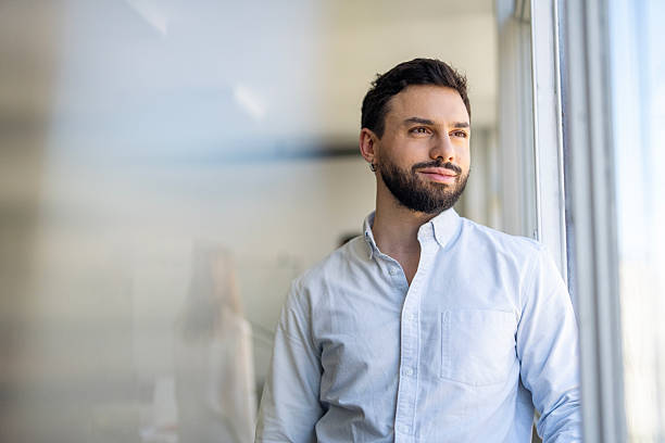 istock Non-binary businessperson looking confidently at the city from window. 2244871420