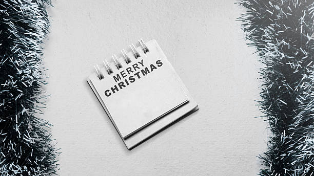 Greeting of Merry Christmas text in a notepad on a white background. Mockup or Copy space. Holiday greetings or winter themes. Concept of the Merry Christmas celebration
