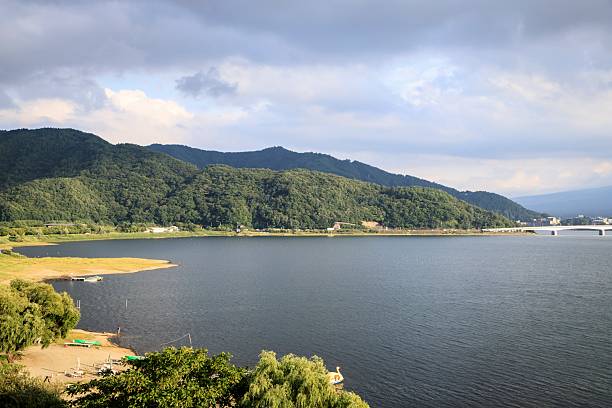 istock Serene Lakeside Landscape with Forested Hills and Bridge at Sunset 2244880192