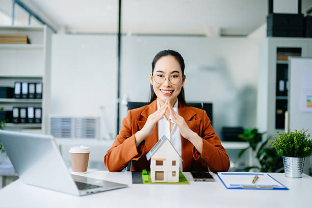 istock Confident real estate agent presenting house models in office. Perfect for property, mortgage, housing market, and professional business themes. 2244884792