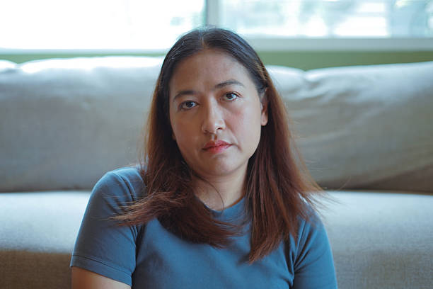 istock Close-up woman's face sitting in front of a sofa inside a house 2244890350