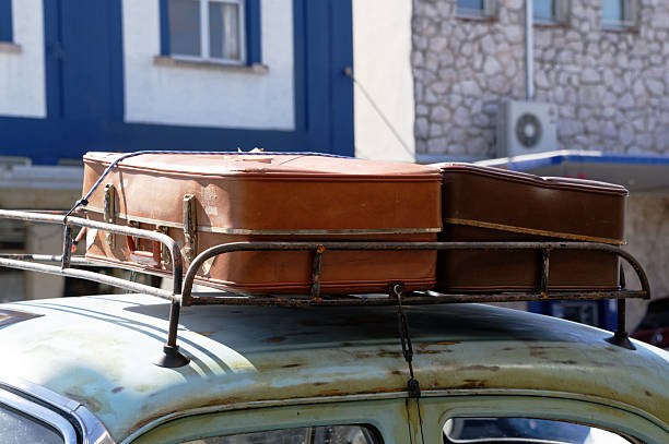 Days gone by, old suitcases are strapped to the roof rack of a classic car