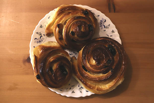 istock Three cinnamon rolls with raisins on a floral plate 2244894883