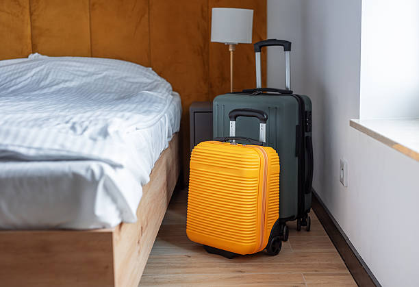 istock Luggage standing beside bed in modern hotel room 2244900913