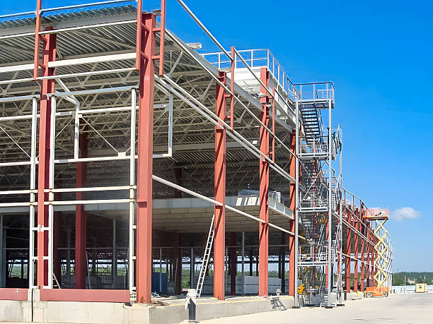 stahlrahmenbau eines großen gewerbe- oder industriegebäudes unter blauem himmel - erektion stock-fotos und bilder