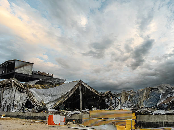 A destroyed building shows damage from a fire or natural disaster under a moody sky.