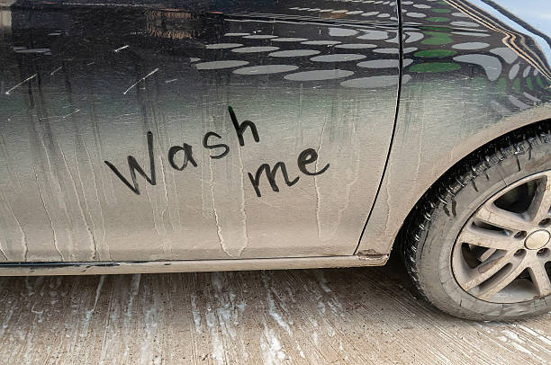 istock A black car covered in dirt with a handwritten message asking for a wash. 2244903419