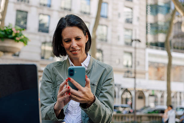 istock Smiling woman using smartphone outdoors in urban setting 2244907264