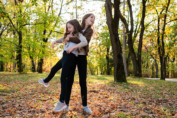 istock Happy sisters playing outdoors embracing in autumn park 2244907672