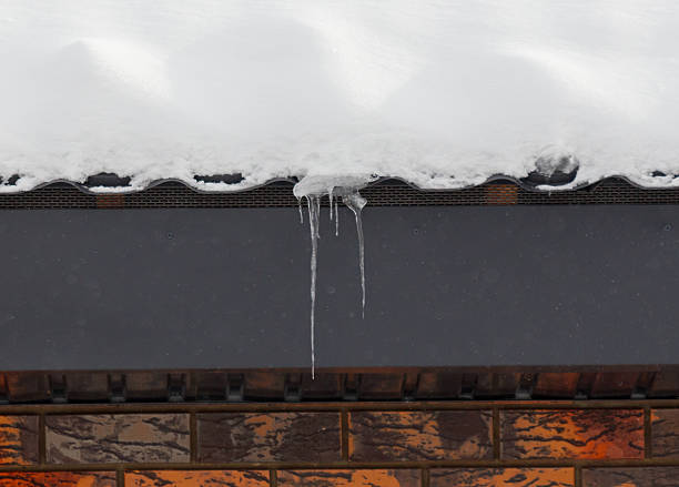 Close-up of shiny icicles on a roof gutter on a blue sky background. Space for copy.