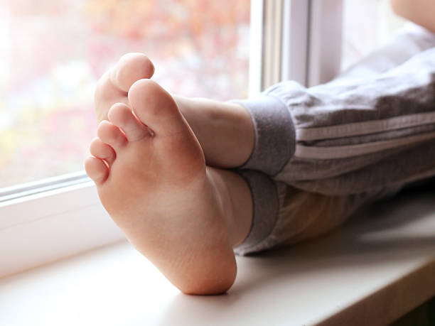 Children's feet on a windowsill at home, sunset light. So close.