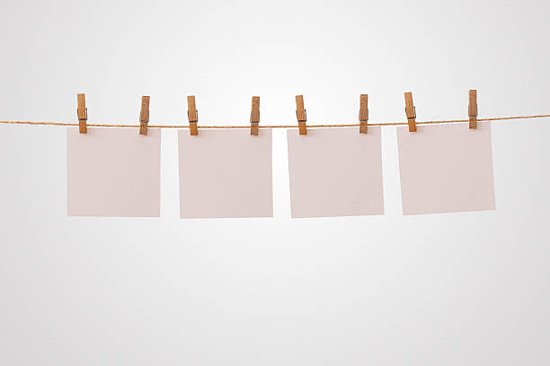 istock Blank paper notes hanging on rope with wooden clothespins isolated on white background for creative message design 2244913009