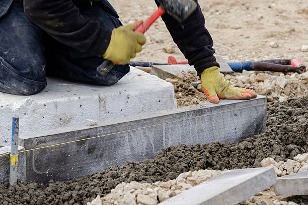 istock Close-up of construction worker leveling concrete and placing edging pin kerb on construction site 2244913079