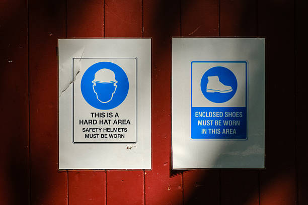 Sunlight falling on two safety workwear requirement signs on a brown wooden wall.