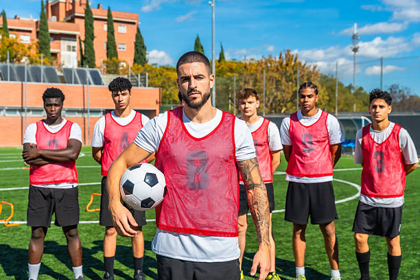 istock Soccer coach holding ball standing with diverse team on field 2244916611