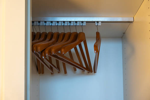 A row of empty wooden hangers inside a wardrobe. Neatly arranged and ready for use in a clean hotel closet.