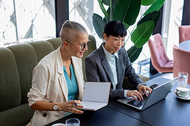 istock Confident female colleagues working together on laptop in stylish workspace 2244924071